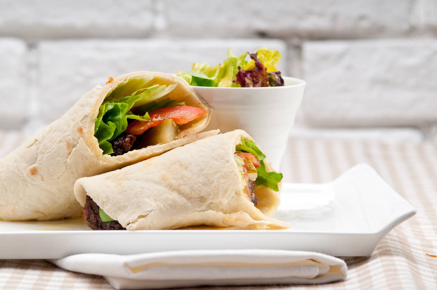 Close-Up Of Wrap Sandwich With Salad On Table