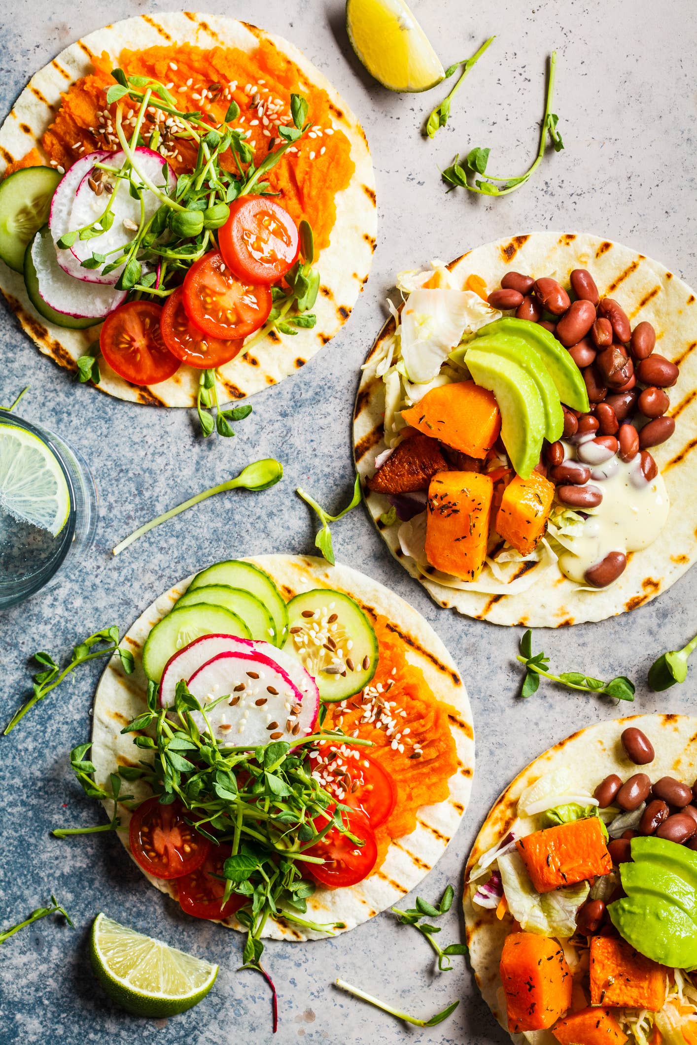 Open vegan tortilla wraps with sweet potato, beans, avocado, tomatoes, pumpkin and  sprouts on gray background, flat lay. Healthy vegan food concept.