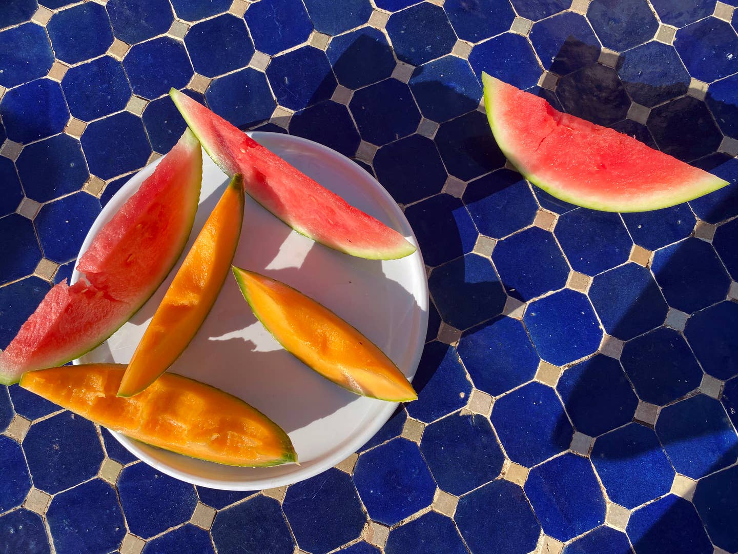 From above fresh slices watermelon and cantaloupe casting a  shadow