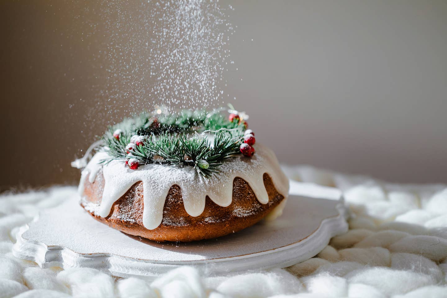 Traditional christmas lemon bundt cake decorated with spruce branch and cranberrys.