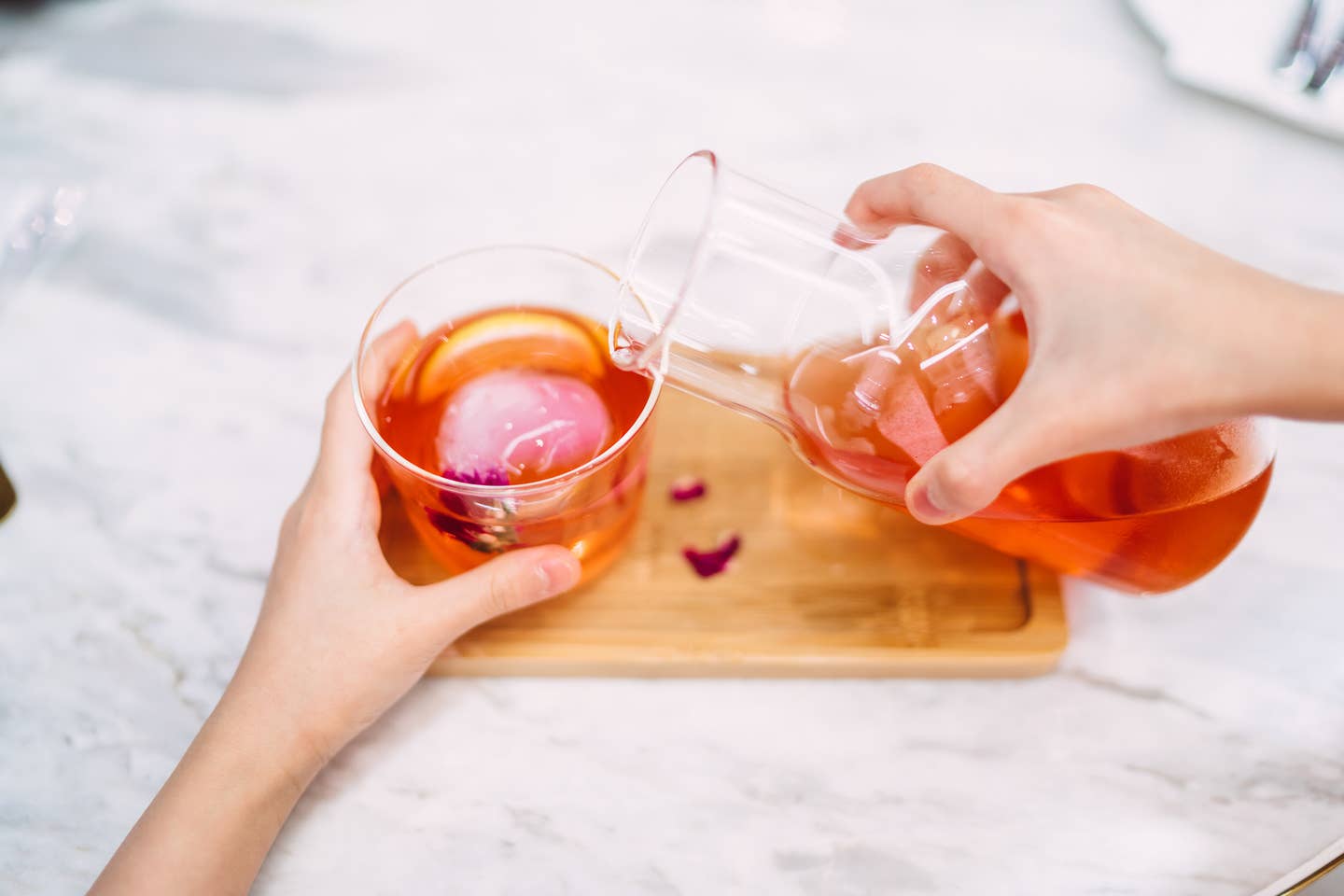 First person perspective of hands pouring tea in drinking glass