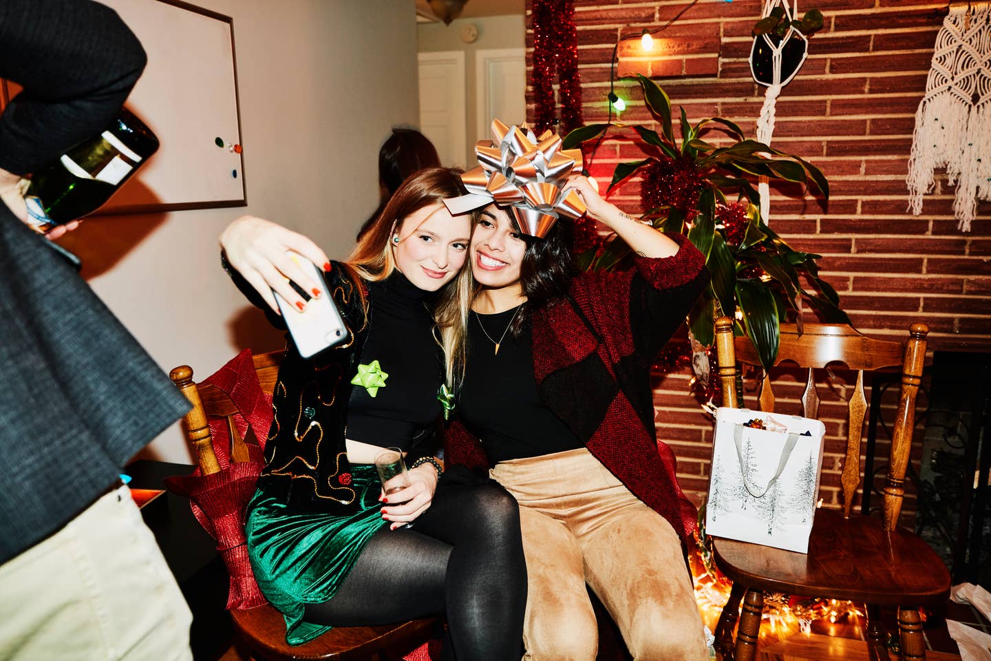 Smiling female friends posing for selfie with bow over their heads during holiday party in home