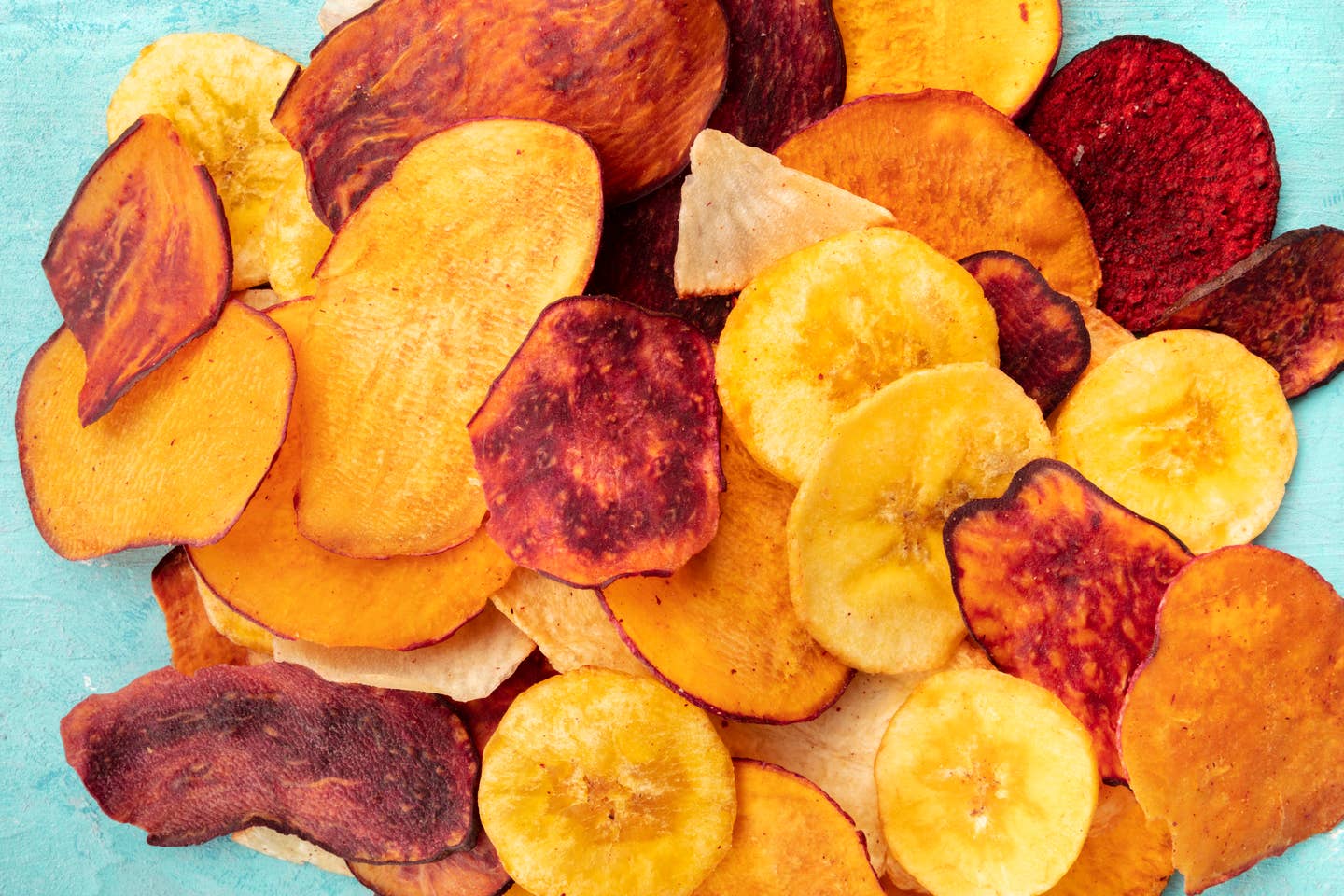 Dry fruit and vegetable chips, healthy vegan snack, a mixed heap on a blue background