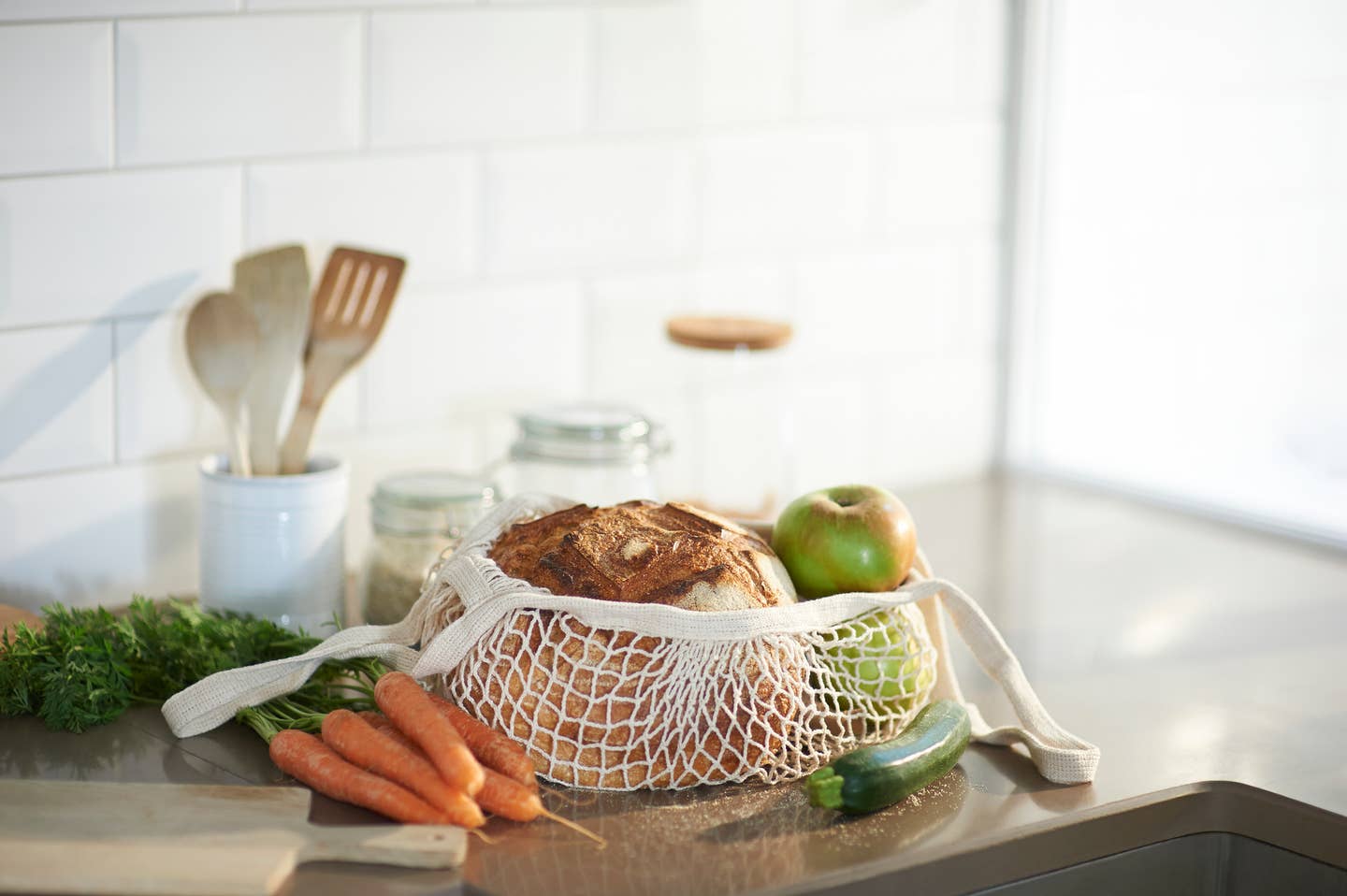 Fresh bread, organic vegetables and fruit on a plastic free zero waste kitchen worktop.