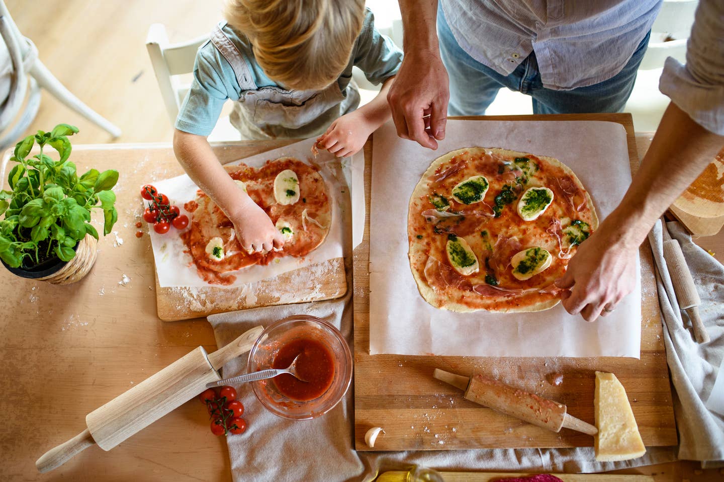 View from above of father with small son making pizza at home, cooking.