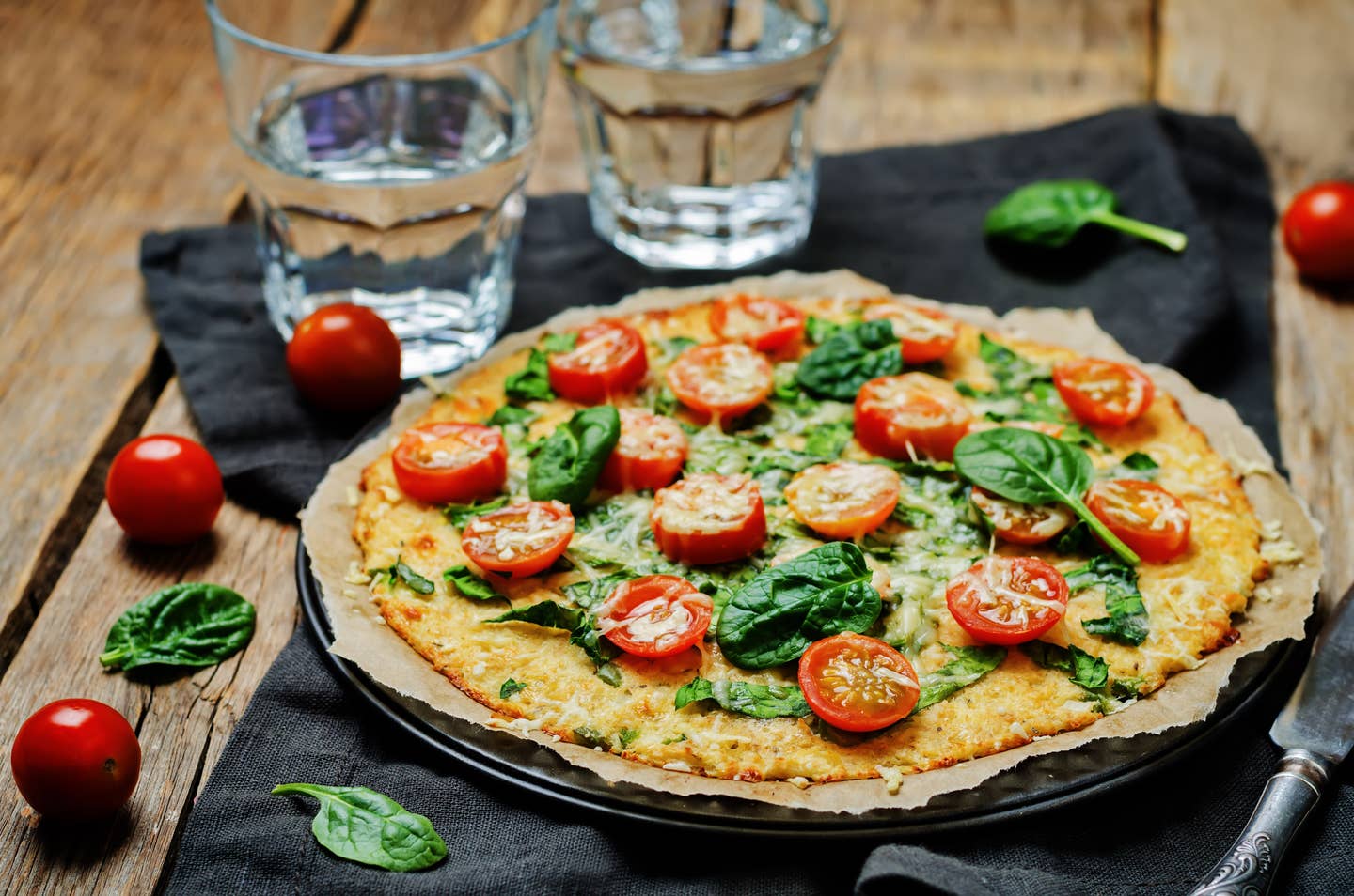 Cauliflower pizza crust with tomato and spinach