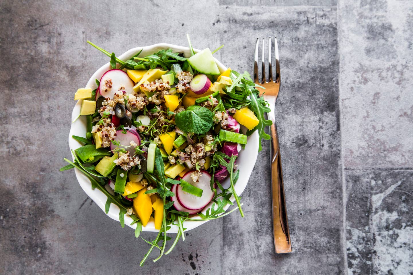 Mango quinoa salad with rocket, avocado, cucumber, red radishes and pumpkin seeds