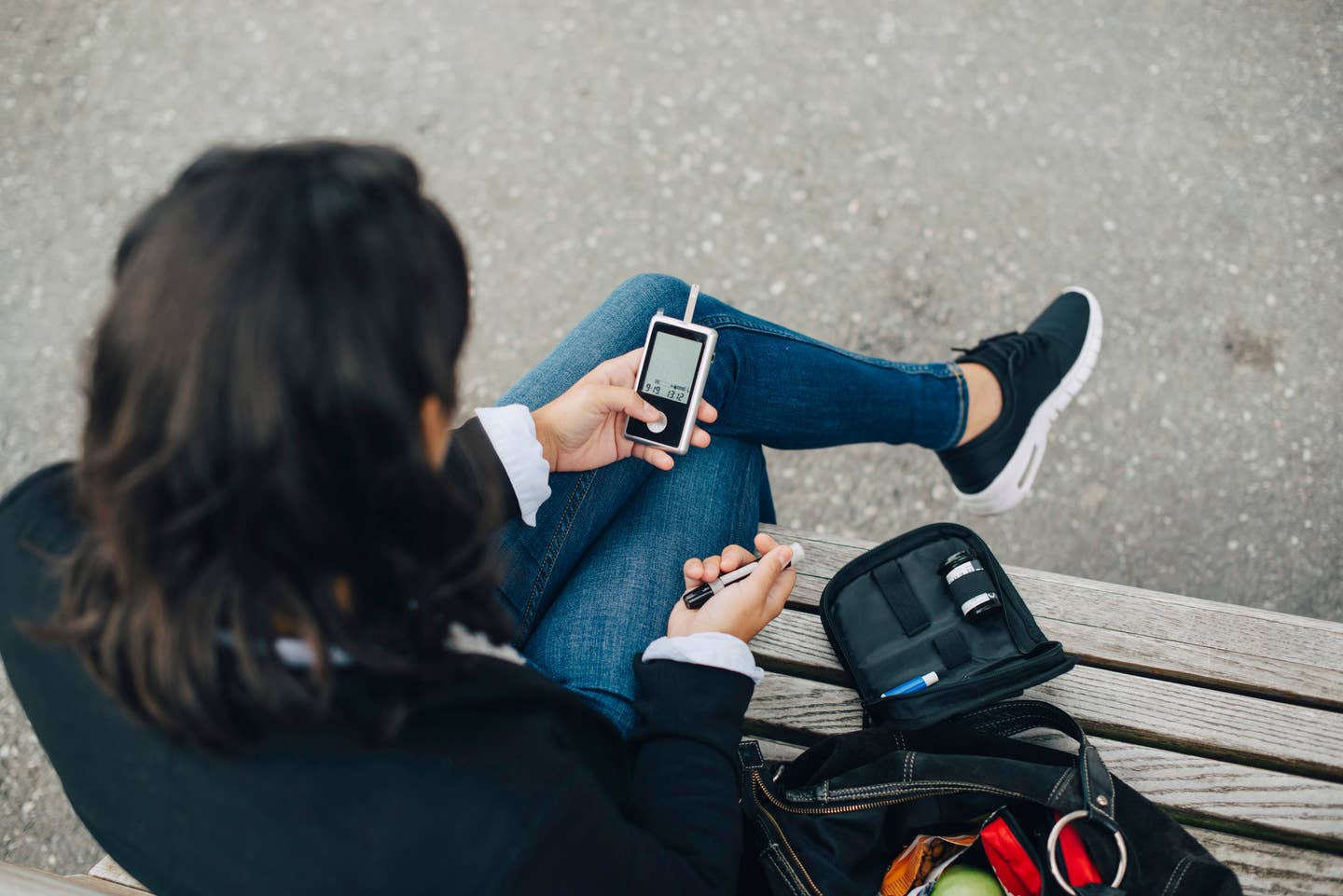 Woman checking blood sugar level while sitting on bench